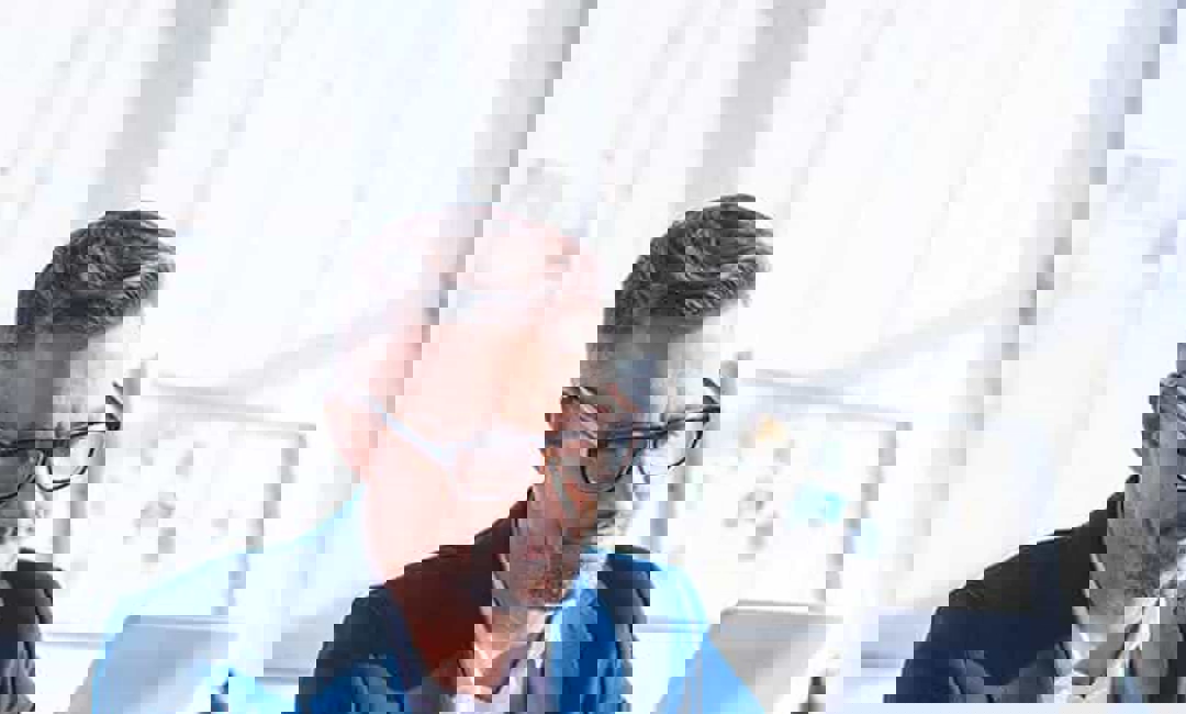 A man with glasses reading from his tablet