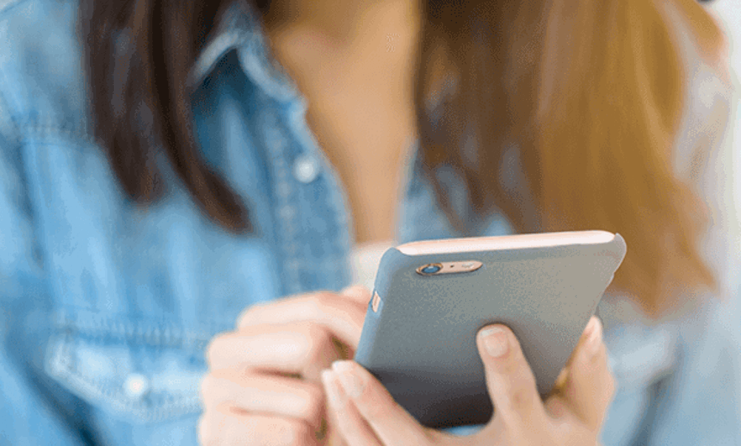 A man walking on the street and looking at his phone.