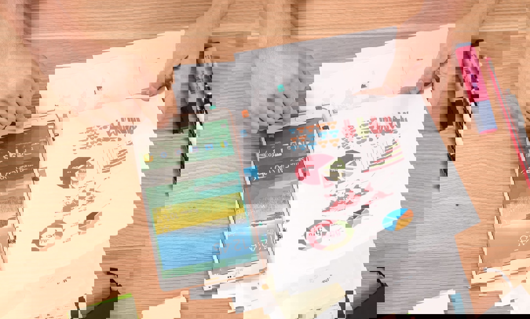 Person pouring over graphs and using a smartphone for research.