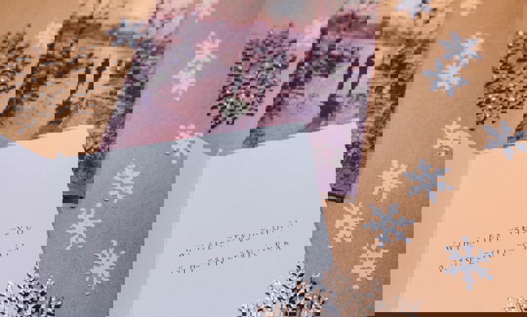 Snowflakes surround a festive card that wishes the receiver a happy holiday.