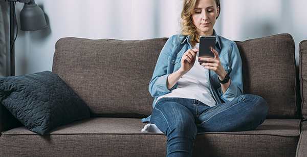 A woman sitting on the couch looking on her phone
